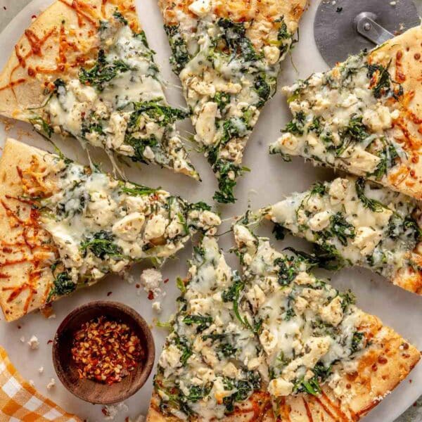 White pizza topped with spinach and mozzarella and cut into slices.