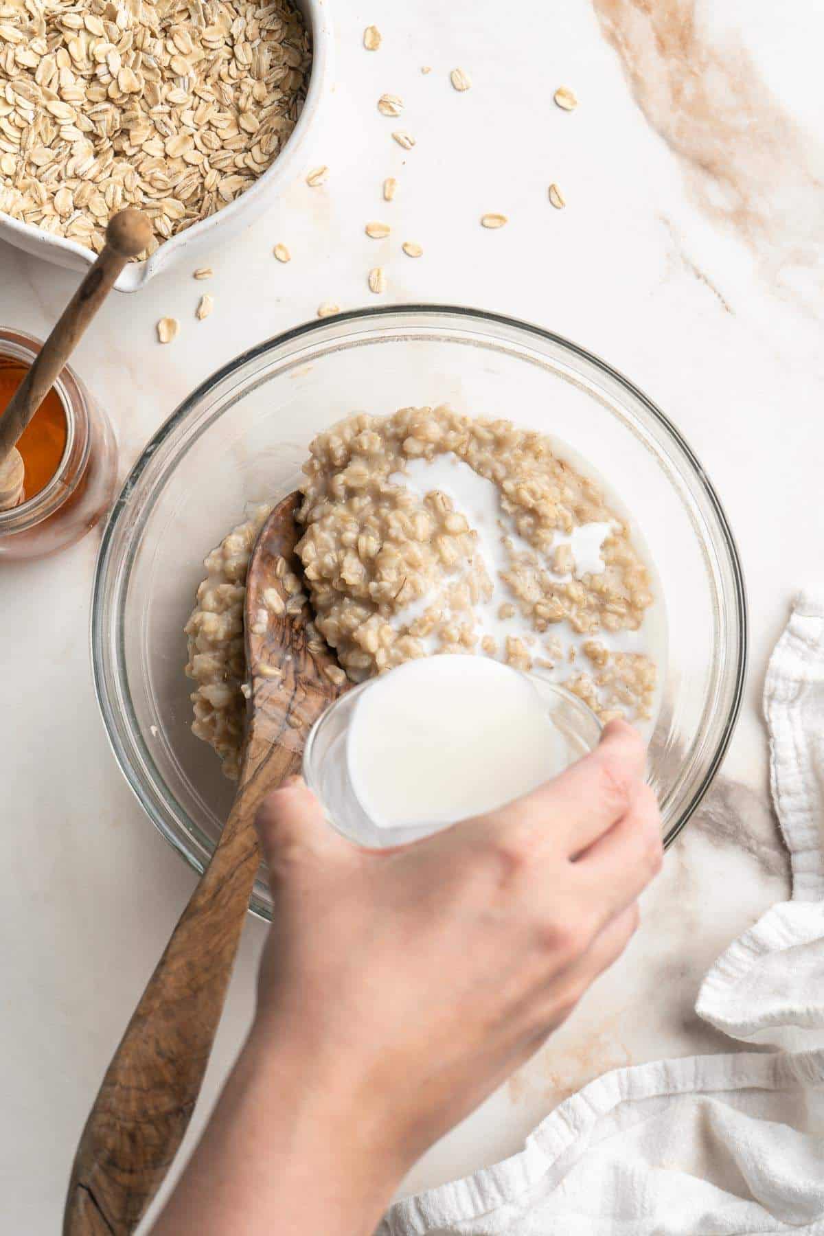 Pouring milk into a bowl of oatmeal.