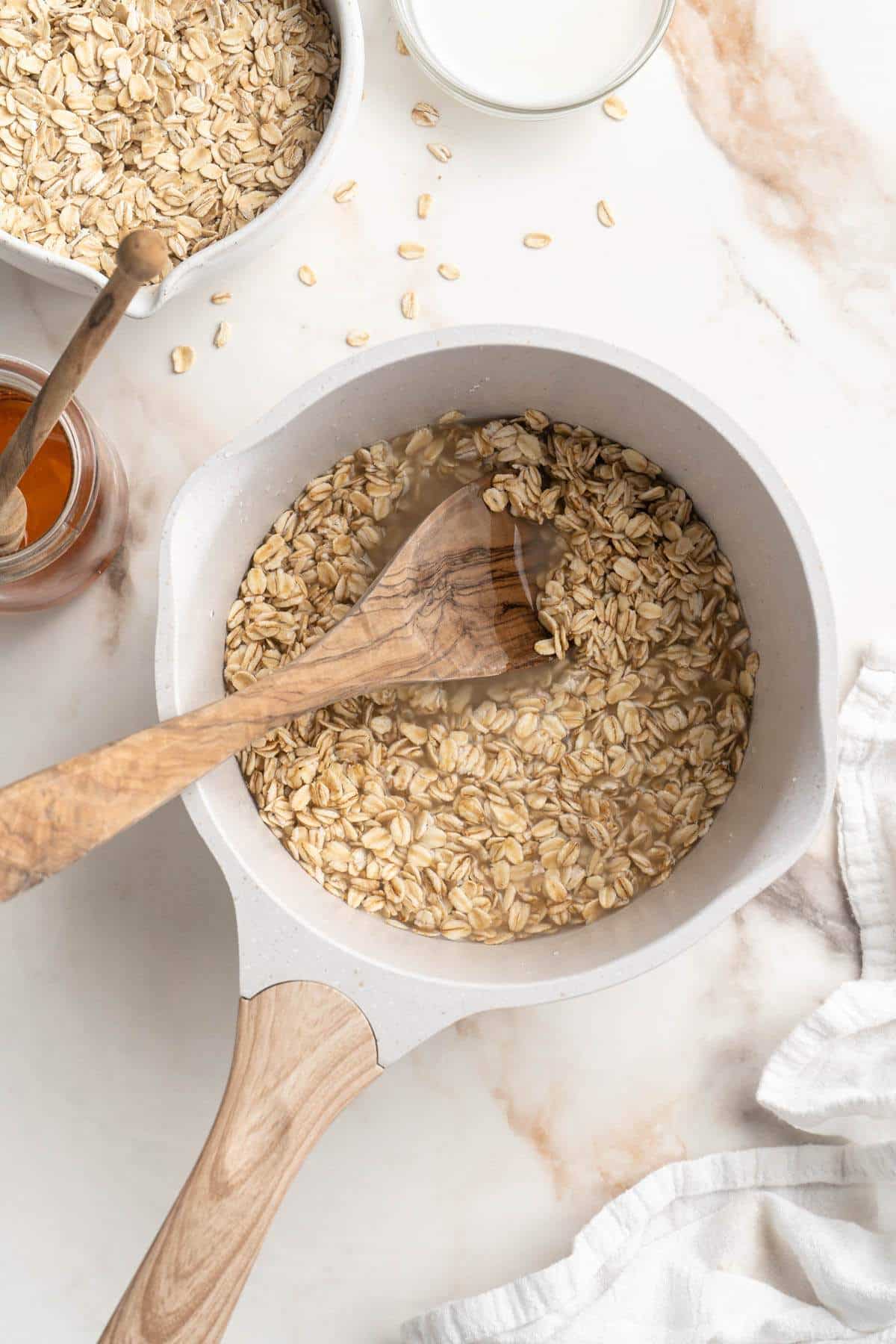 Using a wooden spoon to stir oats with water in a saucepan.