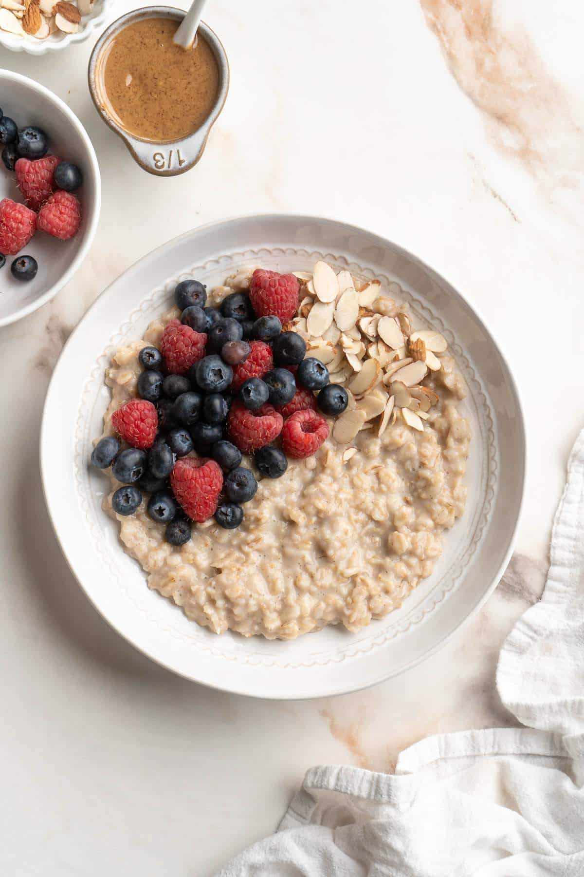 Topping oatmeal bowl with chopped almonds and fresh berries.