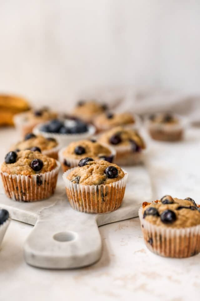 blueberry muffins in a cupcake liner sitting on a marble cutting board