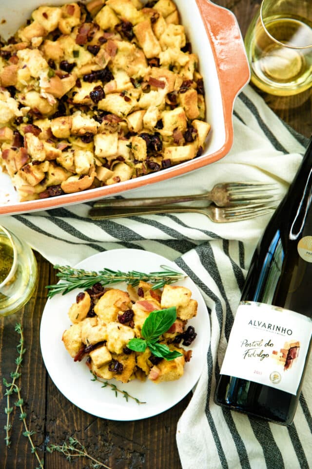 Easy Bacon Apple Stuffing Recipe served on a white plate with a glass of wine on the side