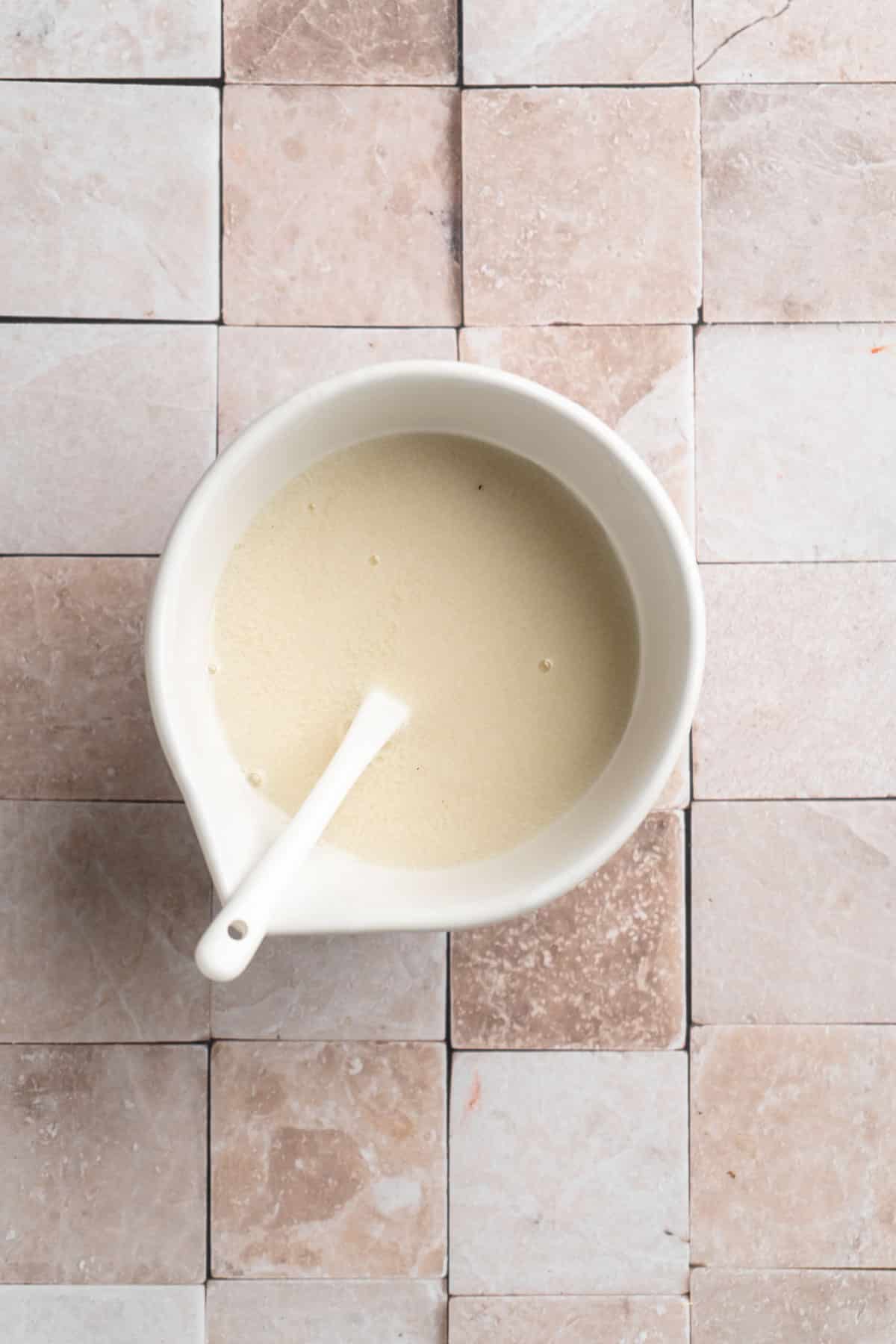 Stirring together vinegar and milk in a small bowl.