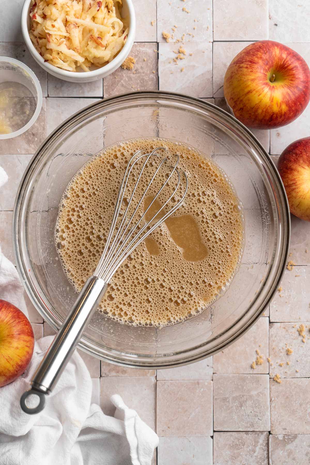 Using a whisk to combine eggs with applesauce and brown sugar.