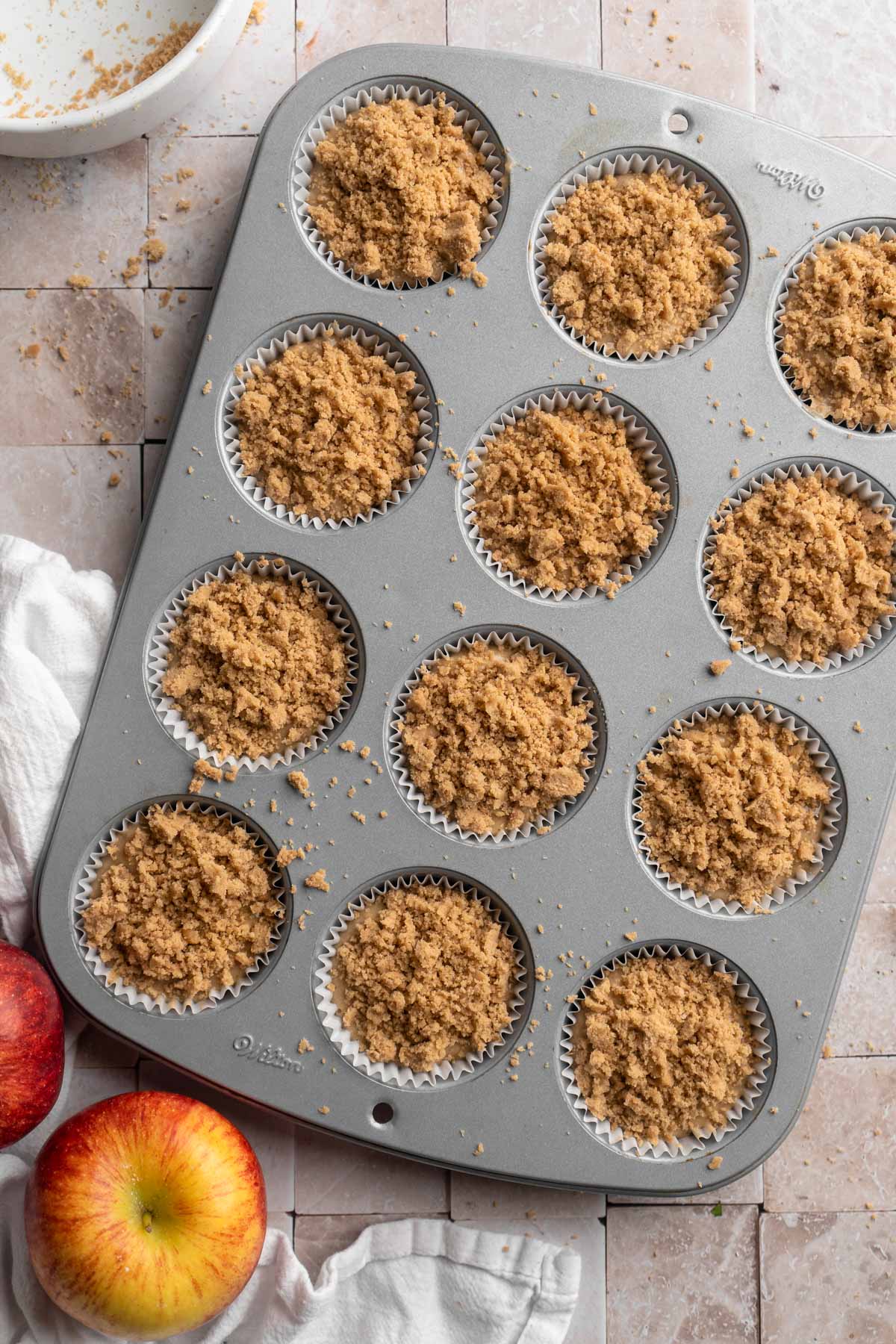 Muffin batter in a muffin pan with crumb topping.