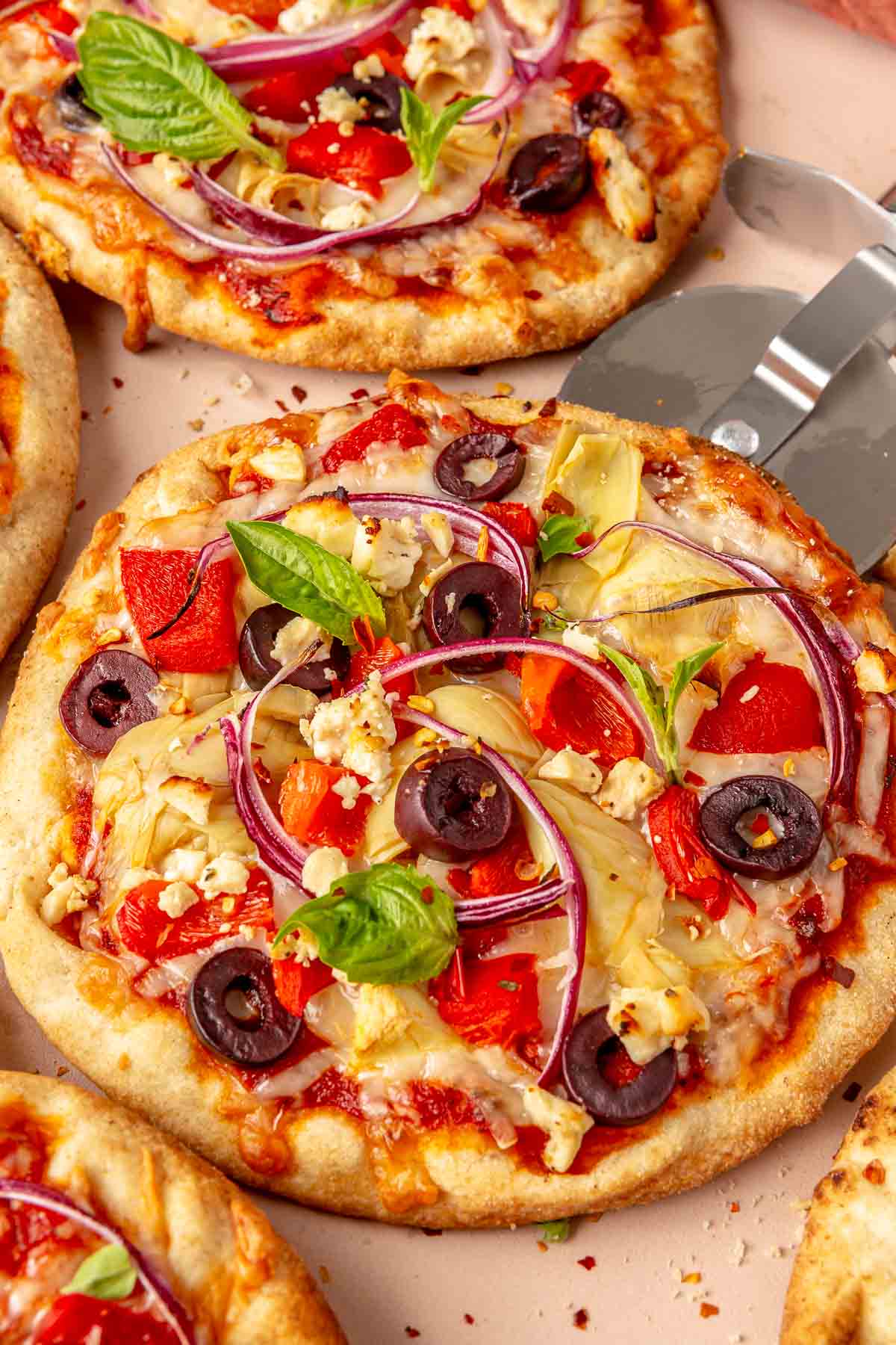 Greek pita pizzas on a pizza stone.