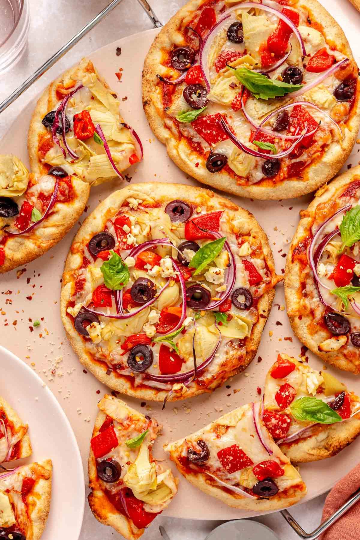 Pita pizzas topped with bell pepper, black olives, red onions and artichokes.