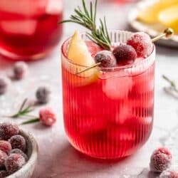 Cranberry cocktail garnished with sugared cranberries, a lemon slice and rosemary.