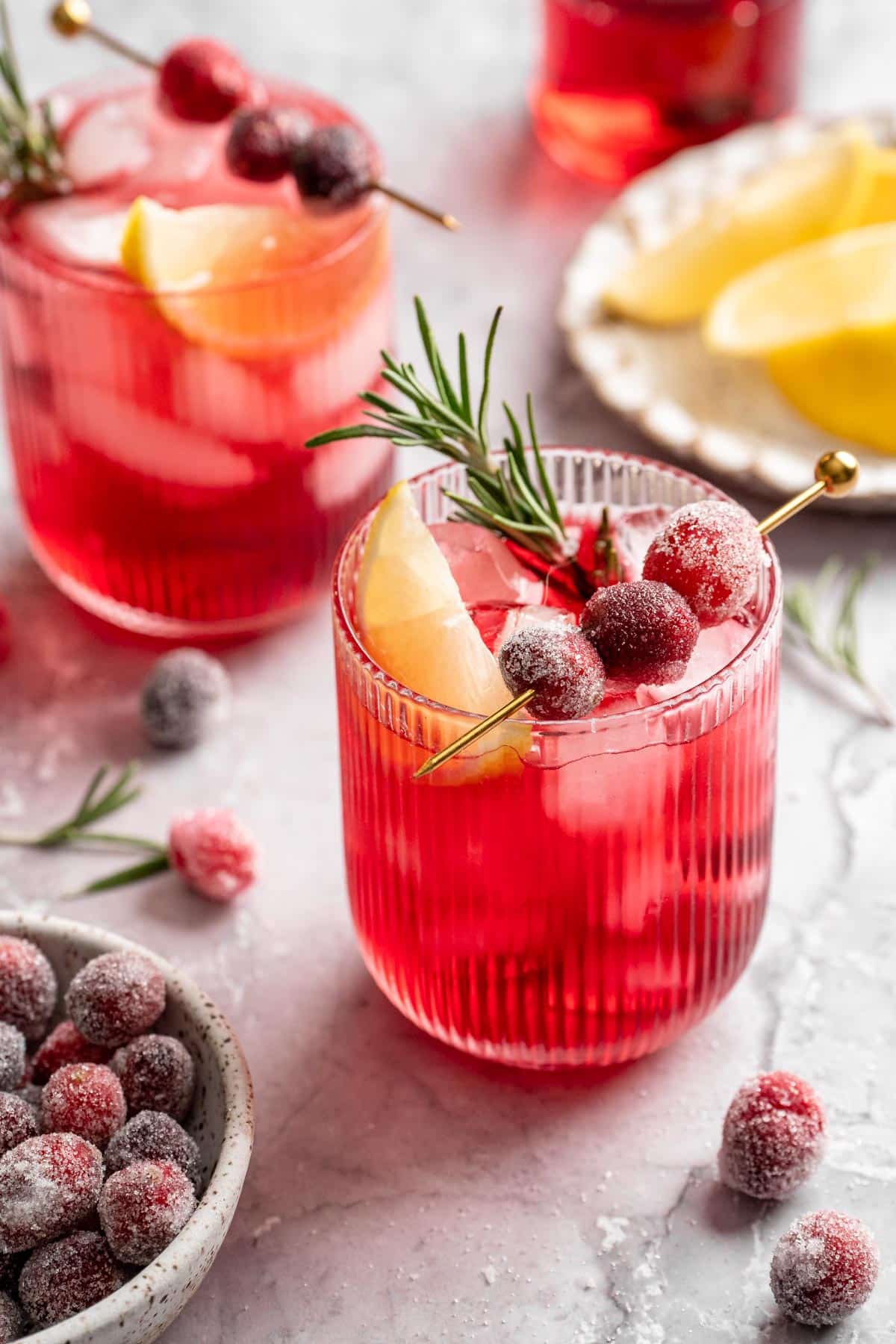 Cranberry mocktail topped with a lemon slice, sugared cranberries and a sprig of rosemary.