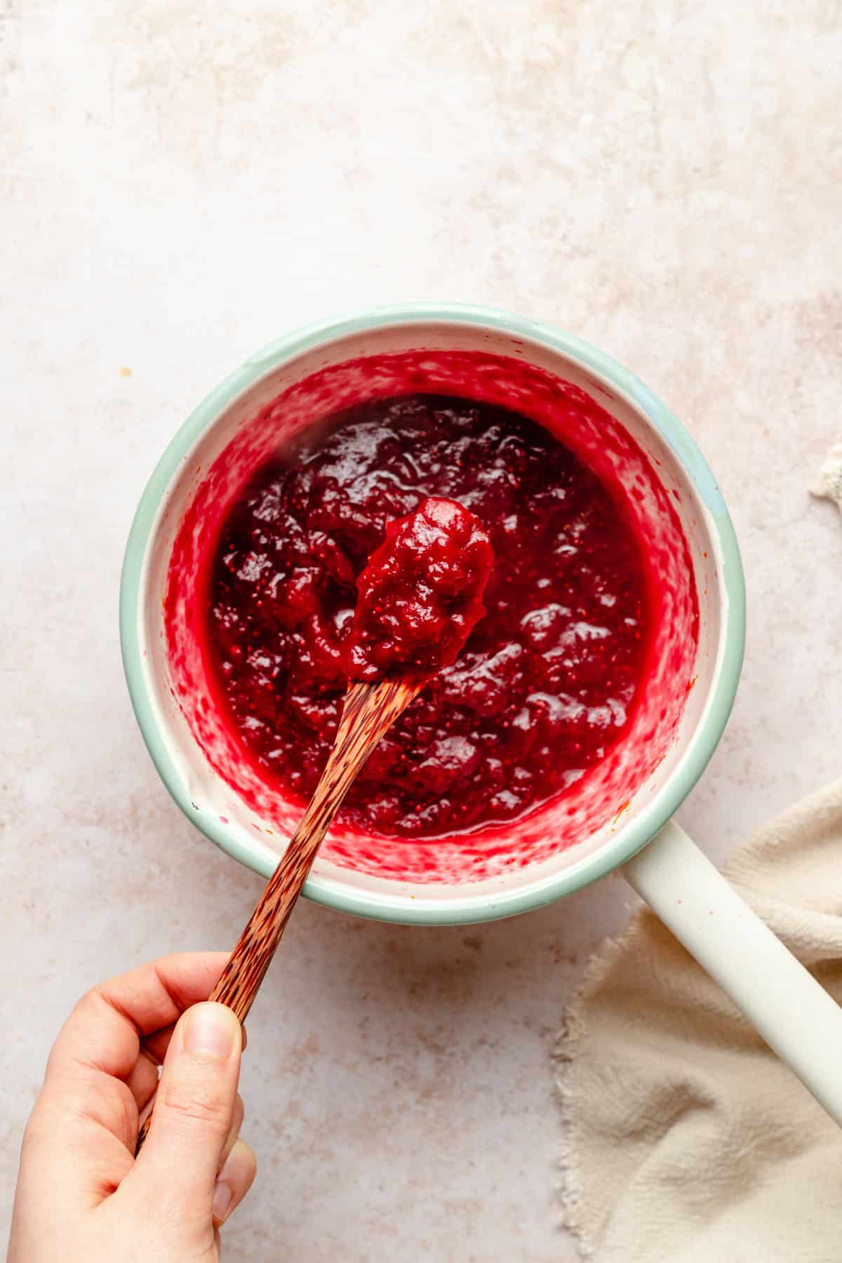 Using a wooden spoon to serve cranberry sauce.