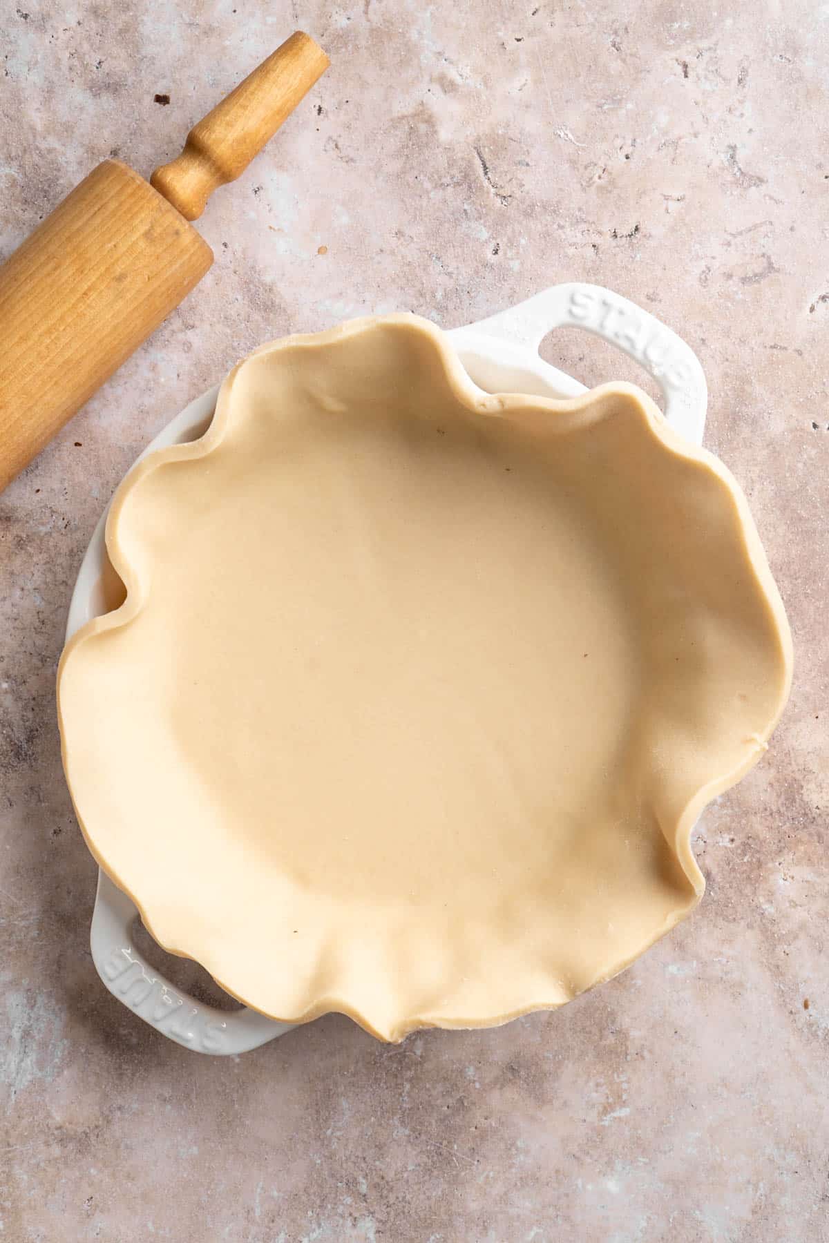 Pie crust draped over a white pie dish.