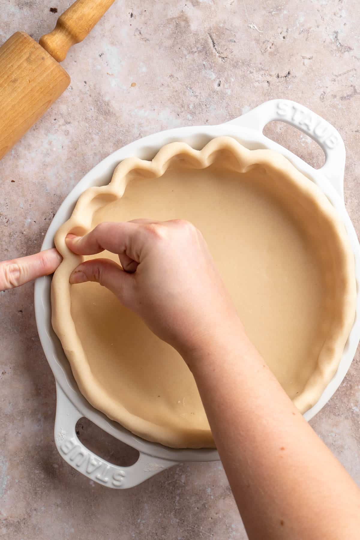 Using fingers and thumb to flute a pie crust around the edges.