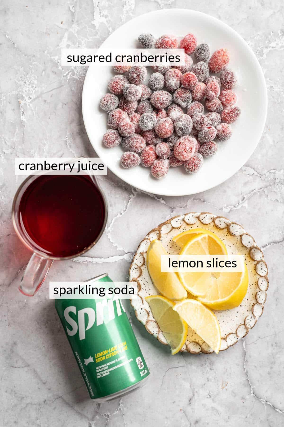 A can of sprite near a bowl of sugared cranberries, lemon slices and cranberry juice.