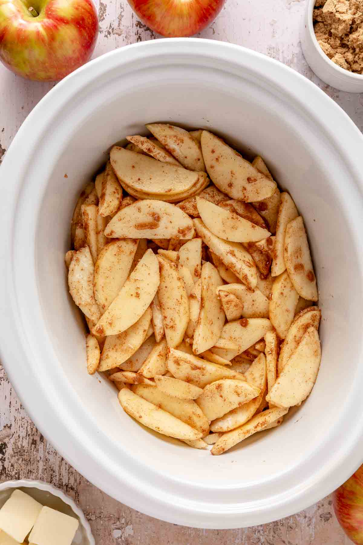 Adding apple slices to a slow cooker.