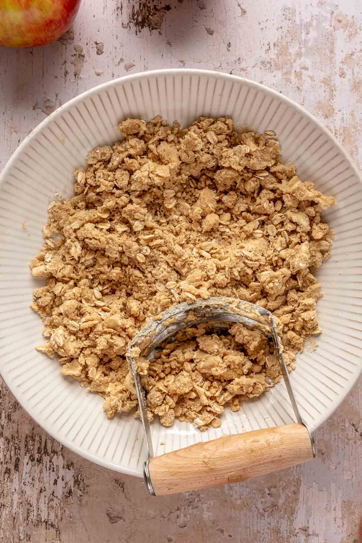 Using a pastry cutter to cut butter into the flour mixture.