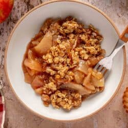 Apple crisp served in a bowl with a fork.