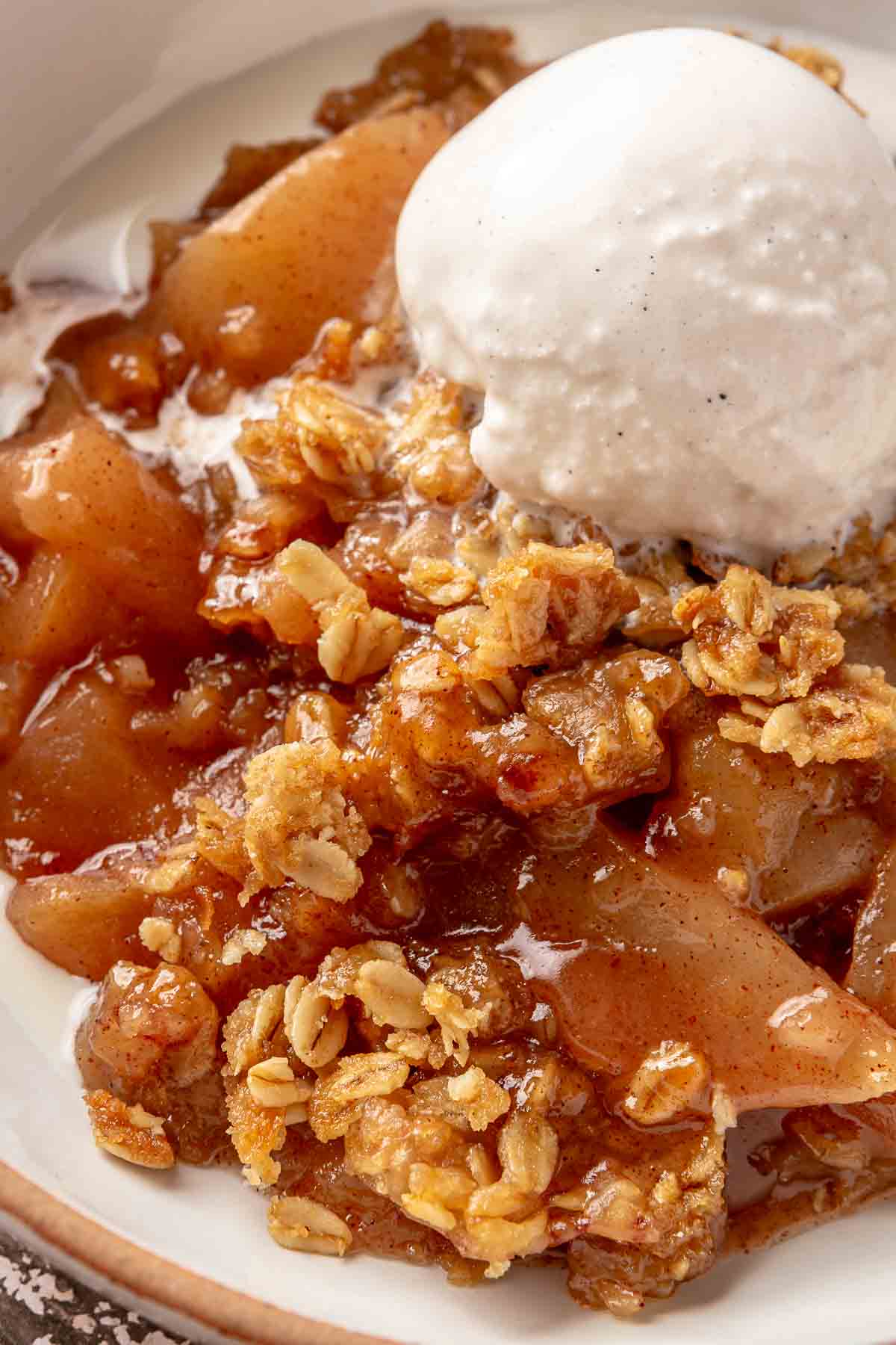 Slow cooker apple crisp topped with a scoop of vanilla ice cream.