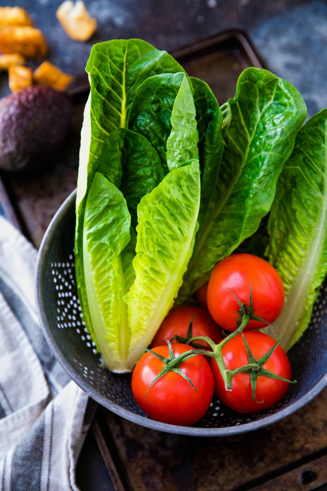 colander filled with tomatoes and romaine lettuce heads