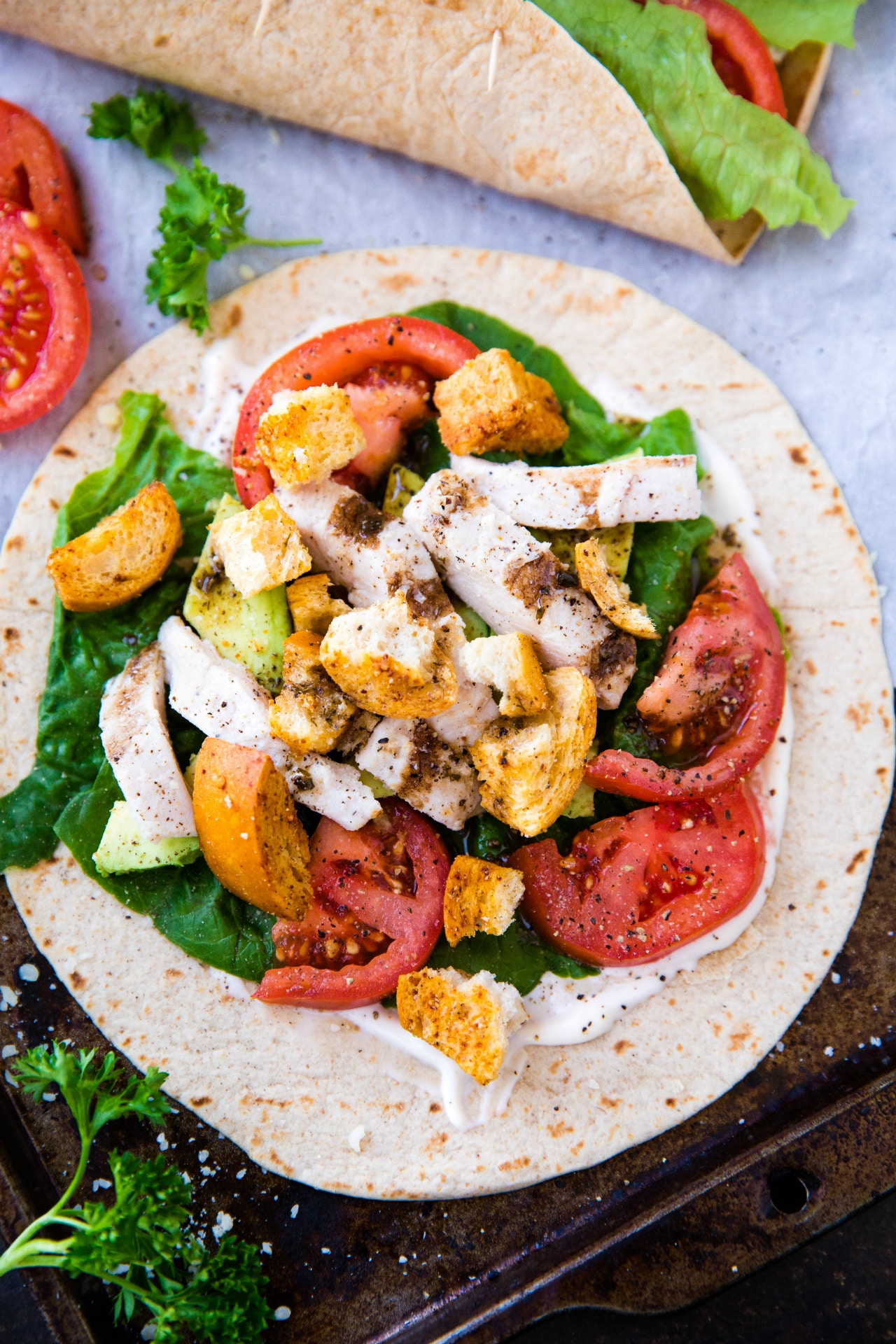 tortilla filled with lettuce, tomatoes, chicken and avocado slices