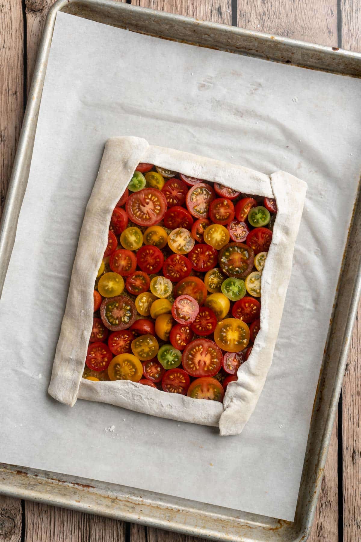 Sides of puff pastry dough folded around the edges with cherry tomatoes in the center.