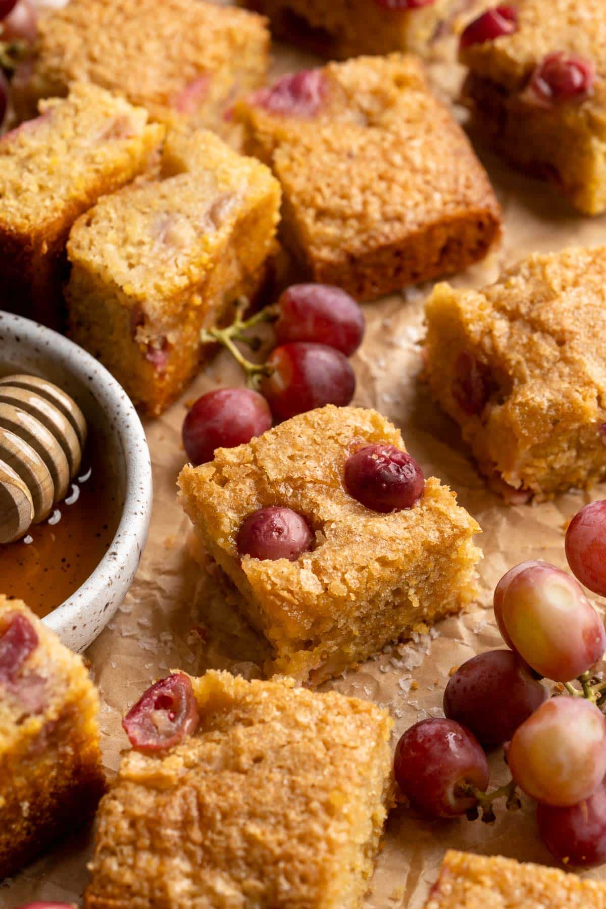 Small squares of grape cake near a small bowl with honey.