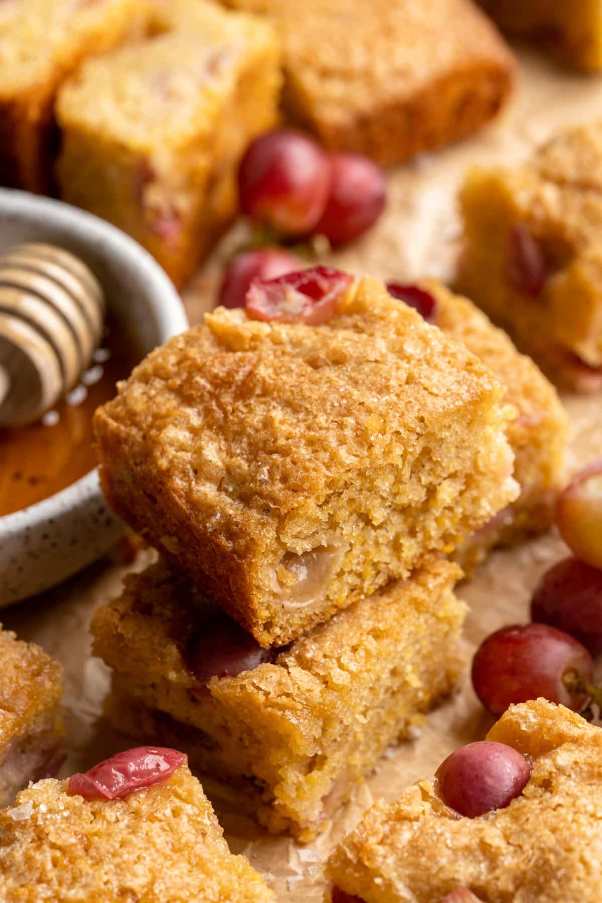 Two squares of cornmeal cake with grapes stacked.