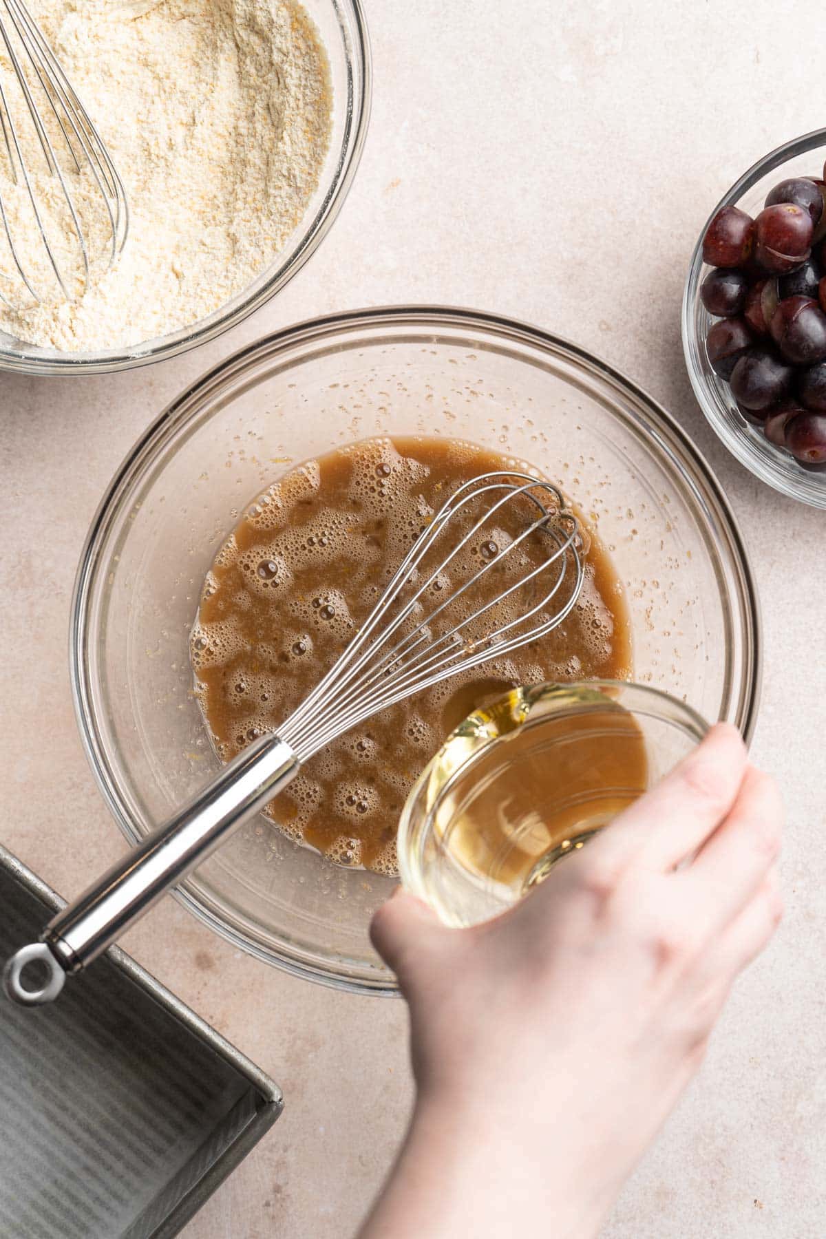 Pouring olive oil into bowl with wet ingredients.