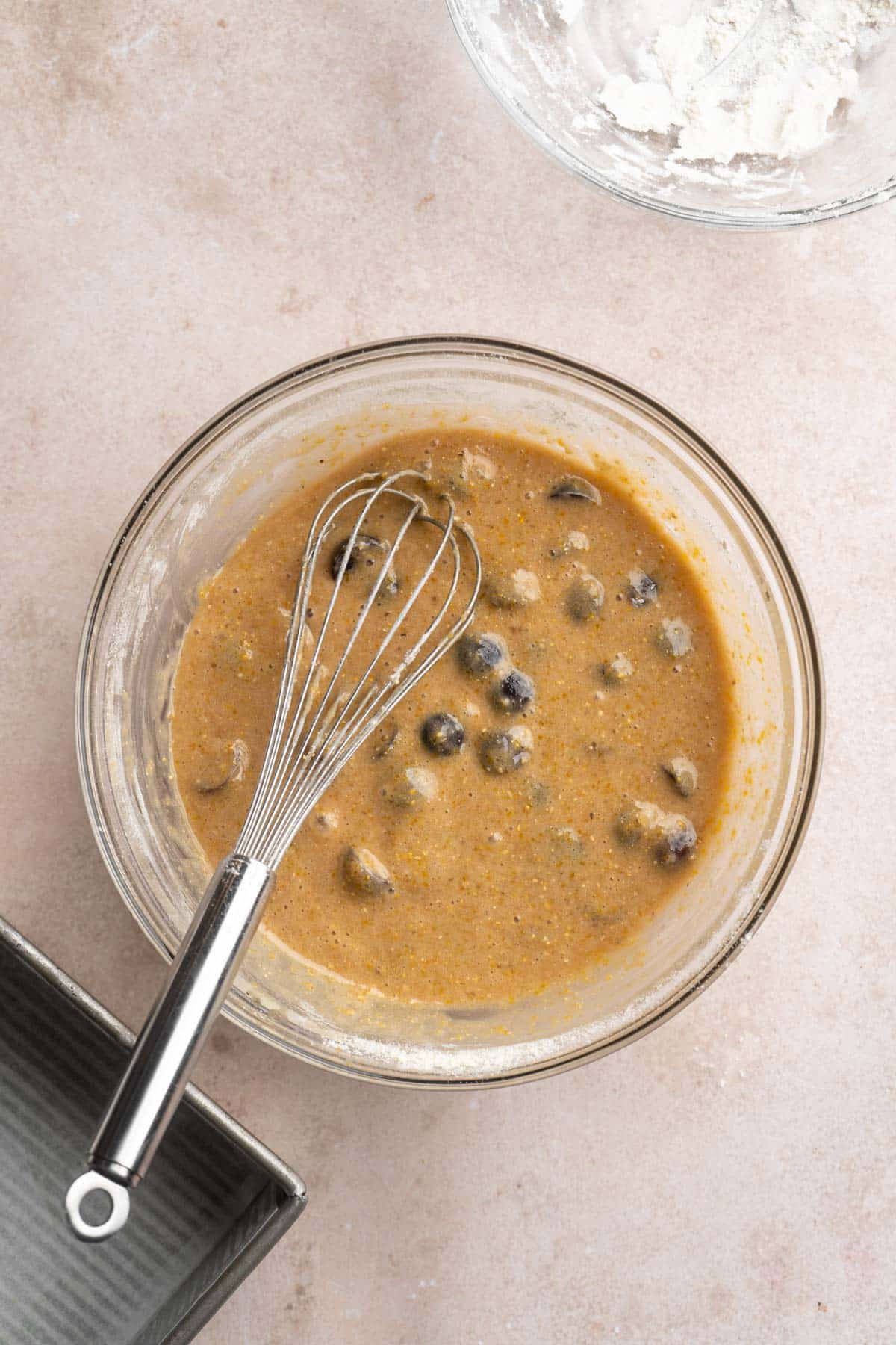 Whisking grapes into cake batter in a large bowl.