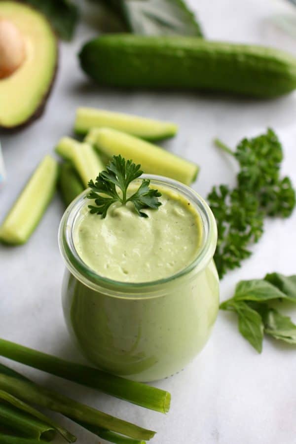 Green Goddess Dressing in a glass jar garnished with fresh parsley