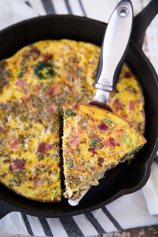 frittata in a cast iron skillet being served with a metal pie server