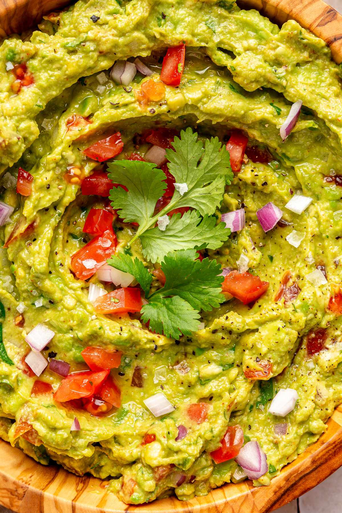 Closeup of guacamole in a bowl garnished with diced tomato and fresh cilantro.