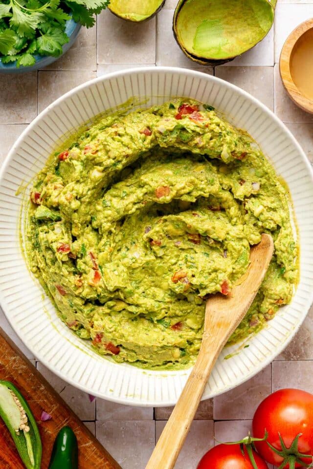 Stirring together mashed avocado with tomato, onion and seasonings.