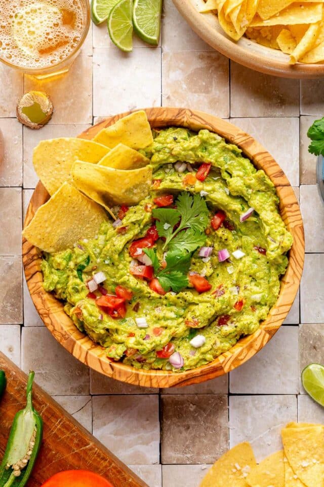 Guacamole recipe with tortilla chips dipped in the bowl.