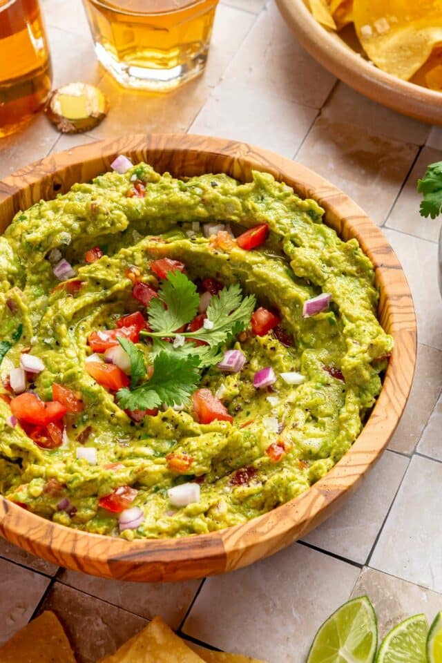 Guacamole recipe served in a bowl with chips and beer.