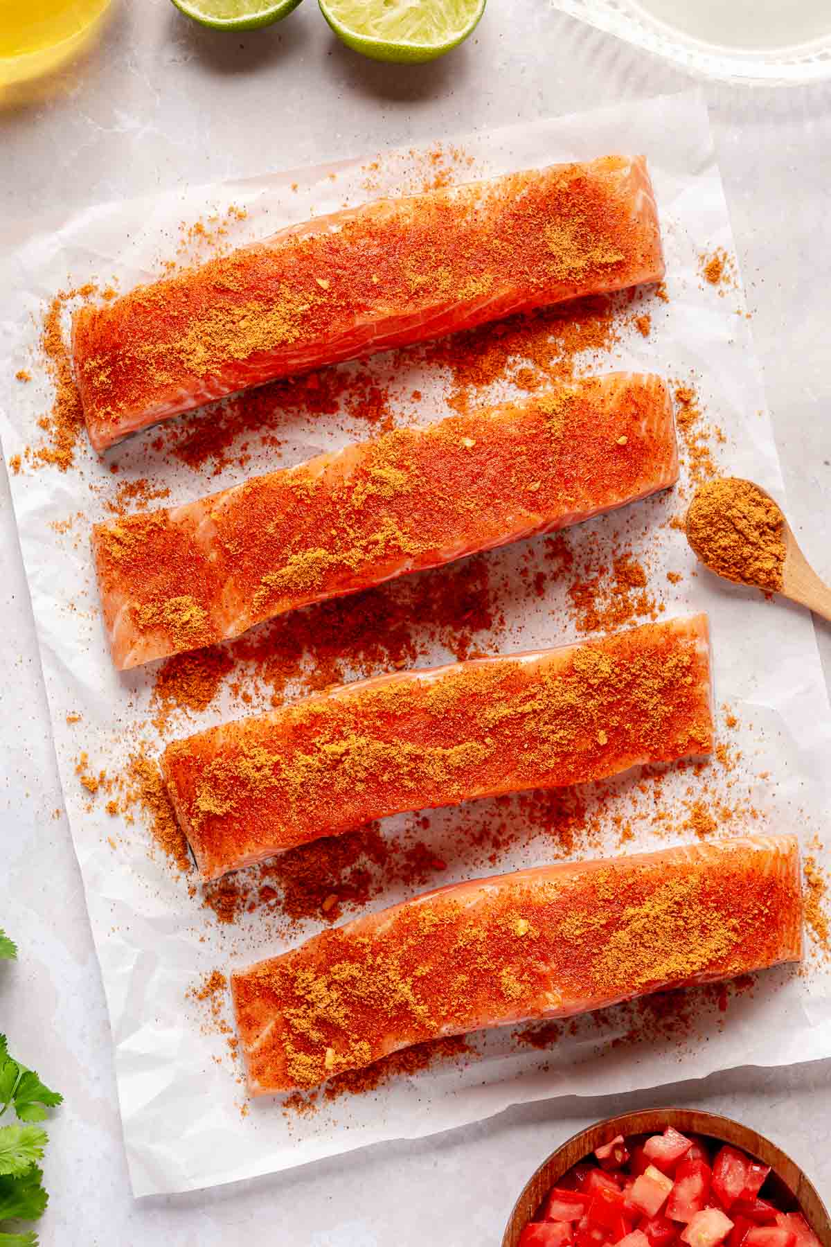 Salmon fillets on parchment paper rubbed with seasoning.