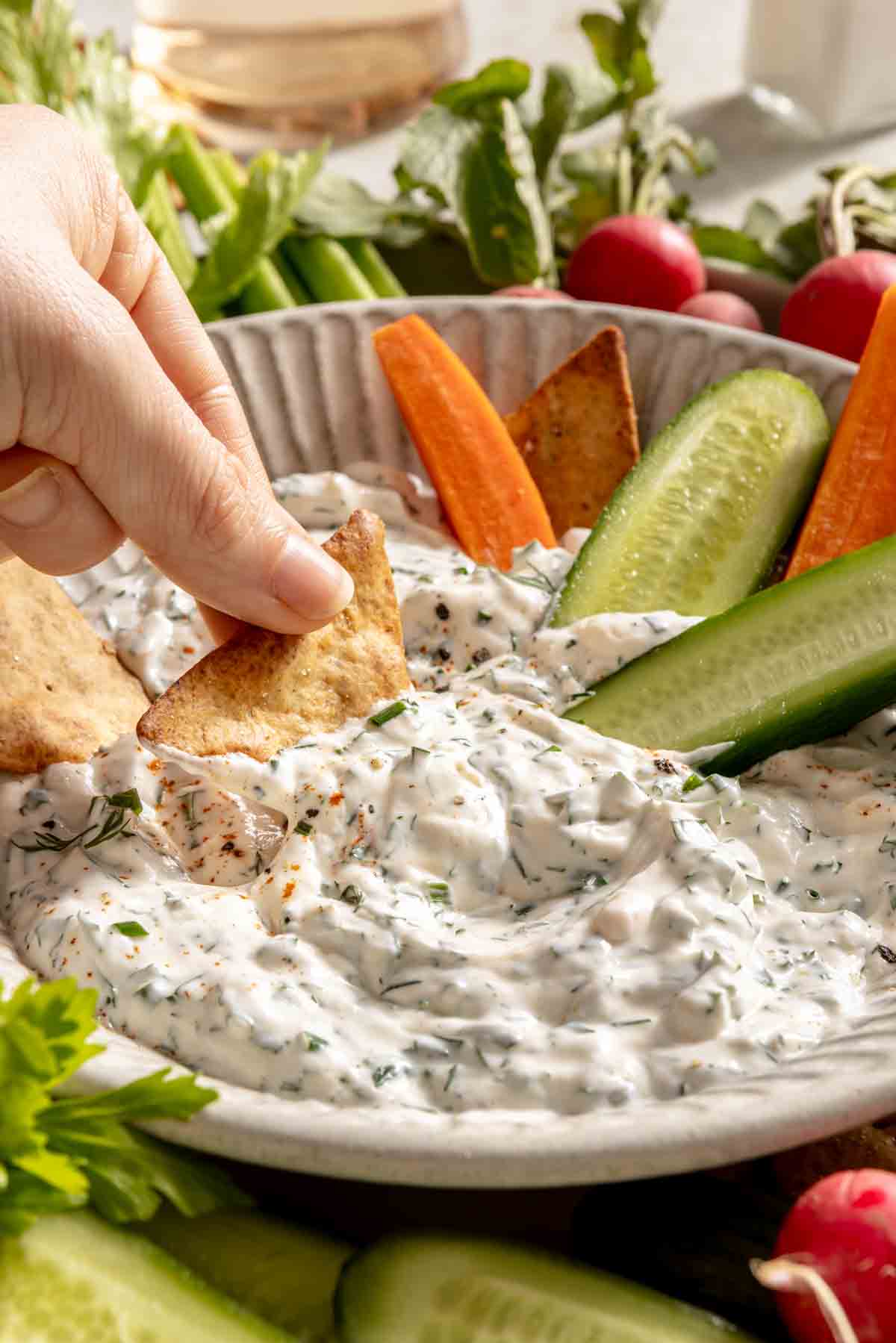 Hand dipping a cracker in ranch dip.