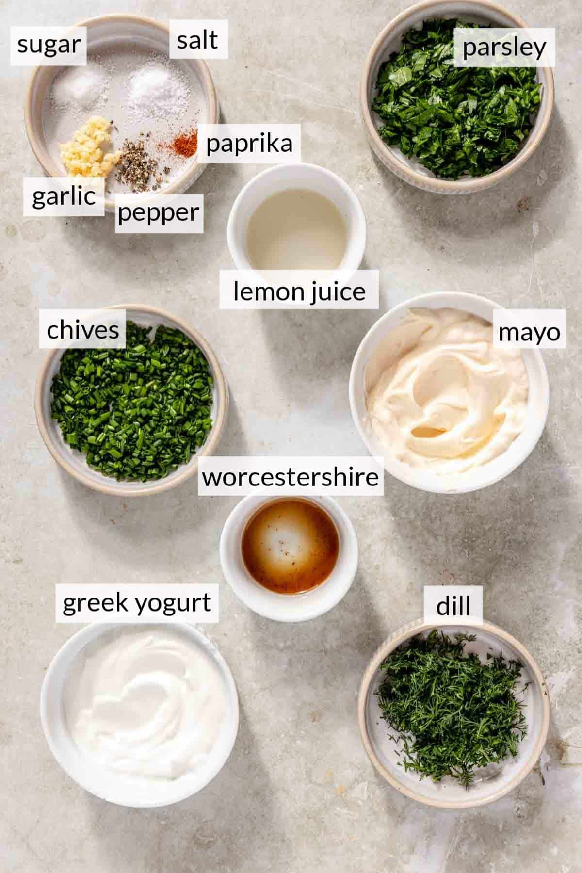 Bowls with mayo, yogurt, seasonings and fresh herbs.