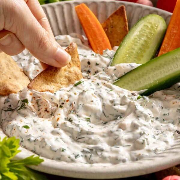 Hand dipping a cracker in ranch dip.