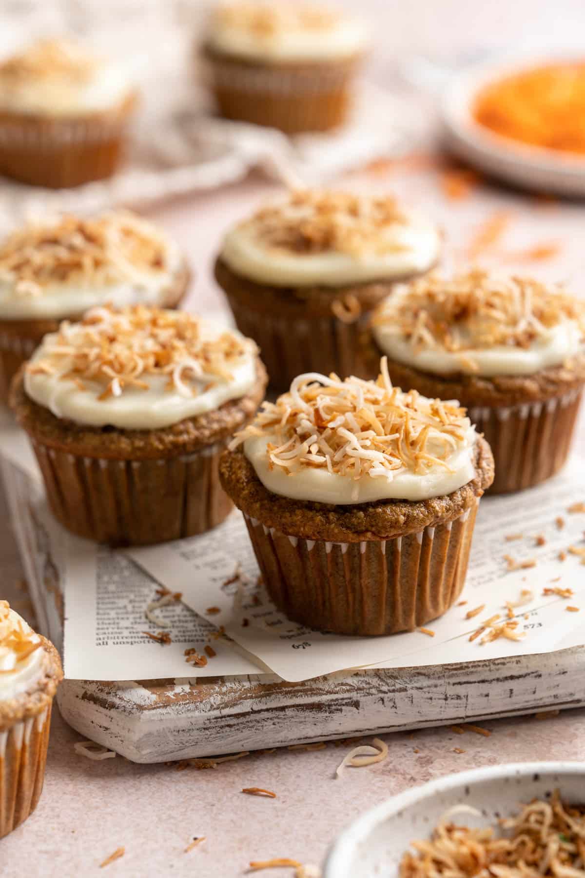 Carrot banana muffins topped with icing and toasted coconut.