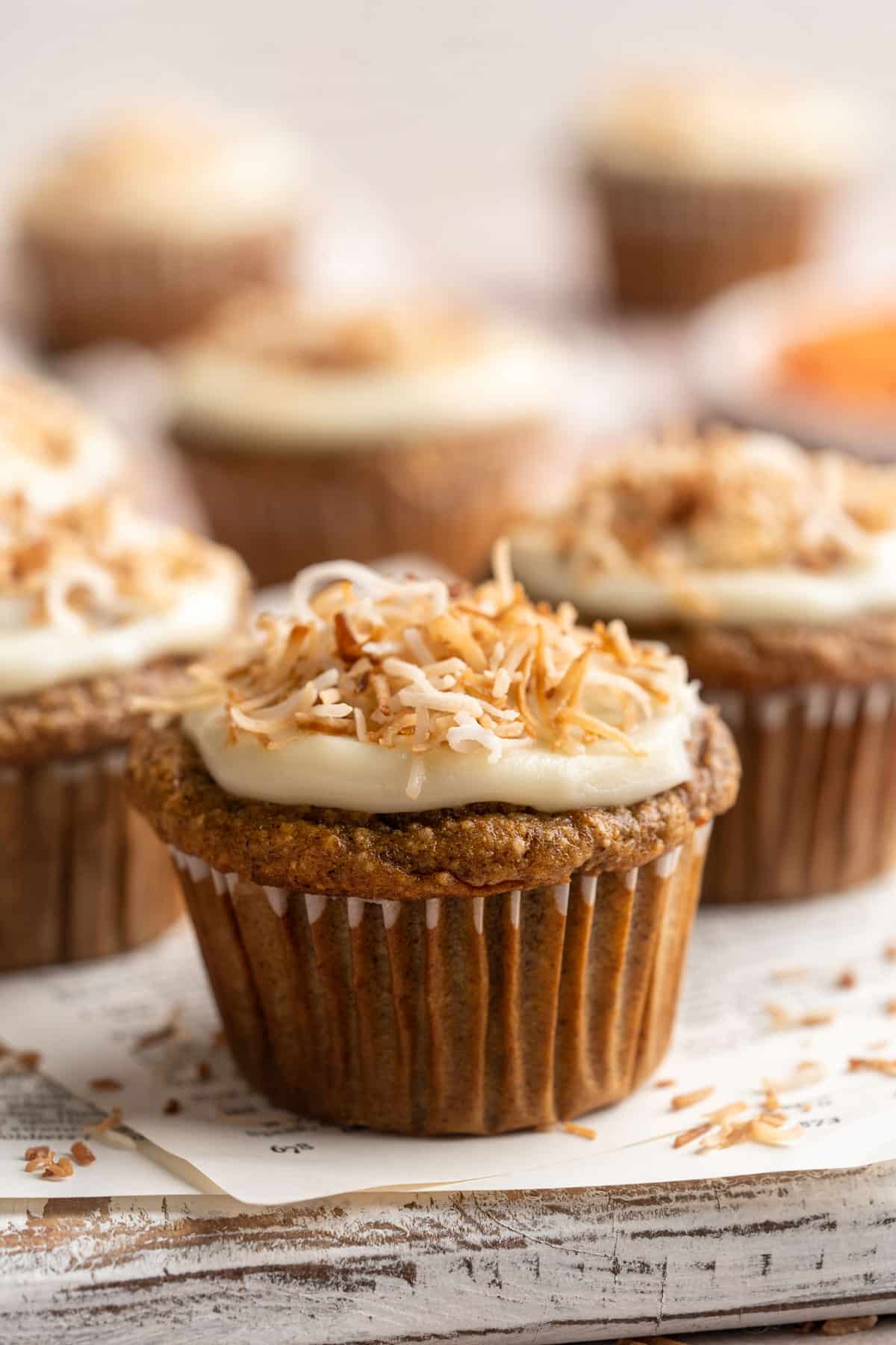 Carrot banana muffins topped with a cream cheese frosting and toasted coconut.