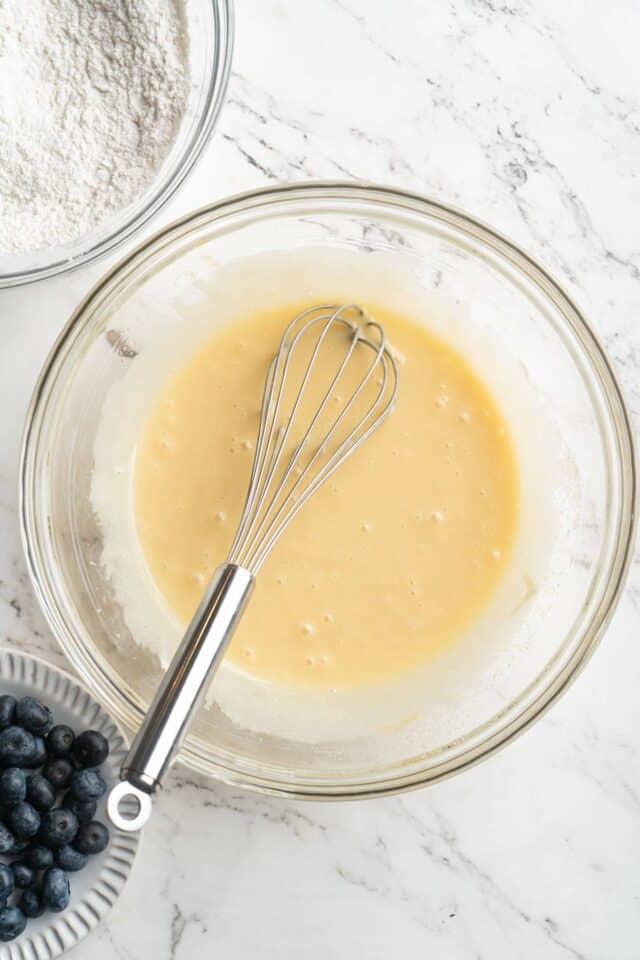 Whisking eggs with sour cream, milk and oil.