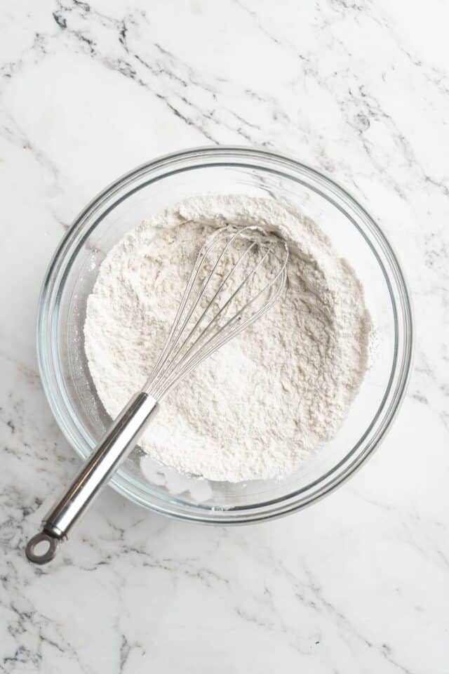 Whisking flour with baking powder and baking soda.