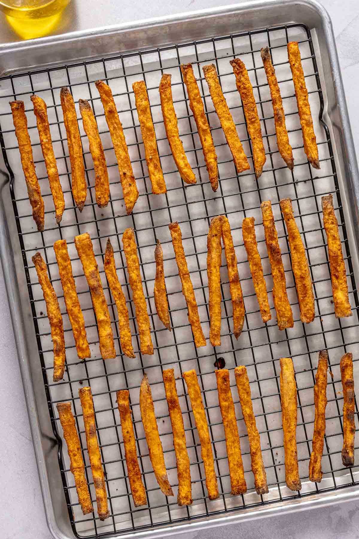 Baked sweet potato fries on a rack on a sheet pan.