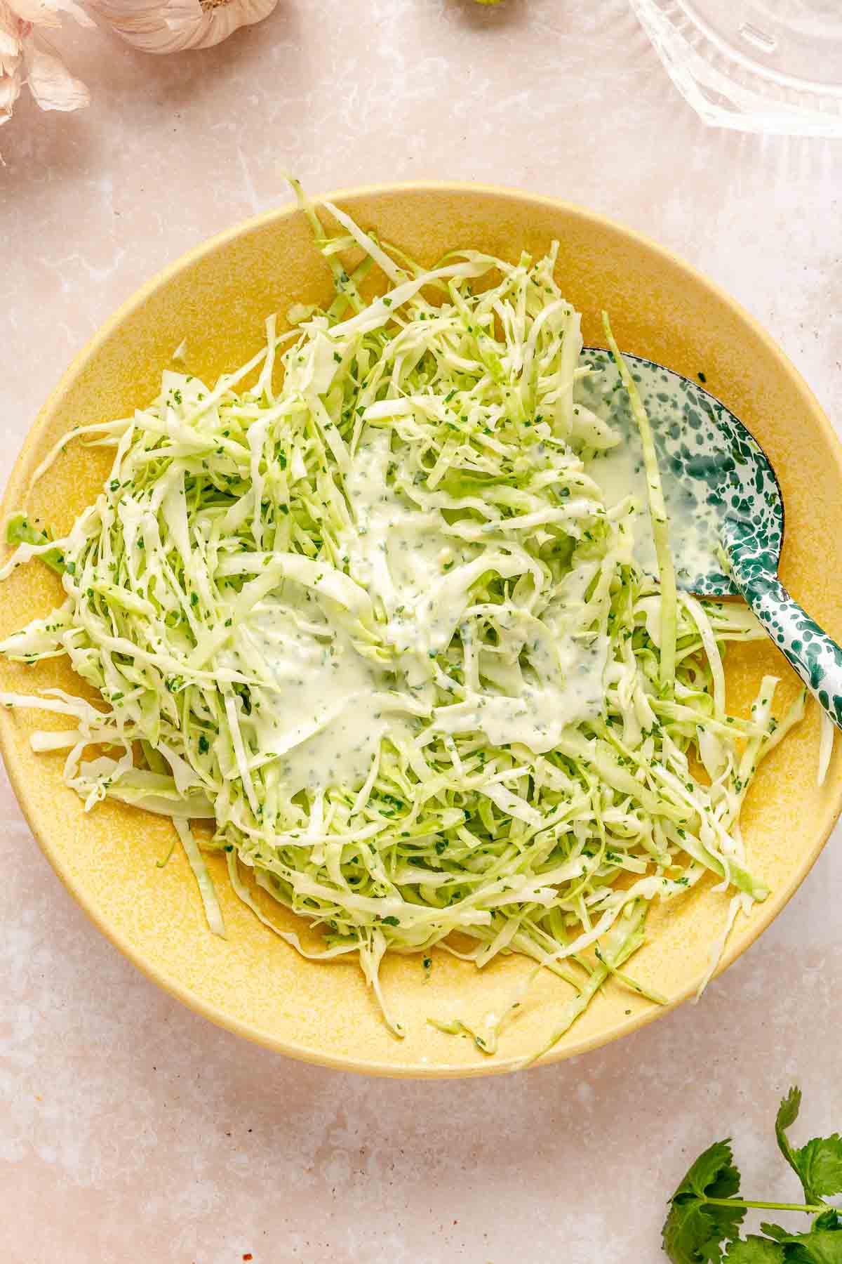 Adding cream sauce to green cabbage slaw.