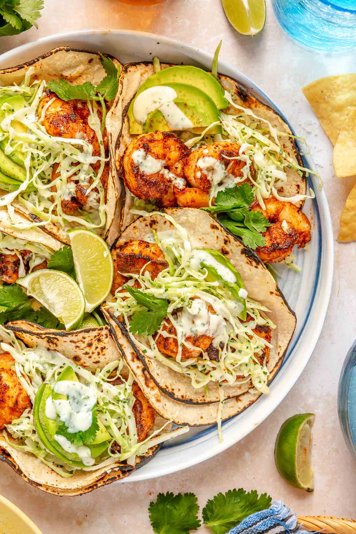 Shrimp tacos with cilantro lime slaw on a plate with lime wedges and avocado slices.