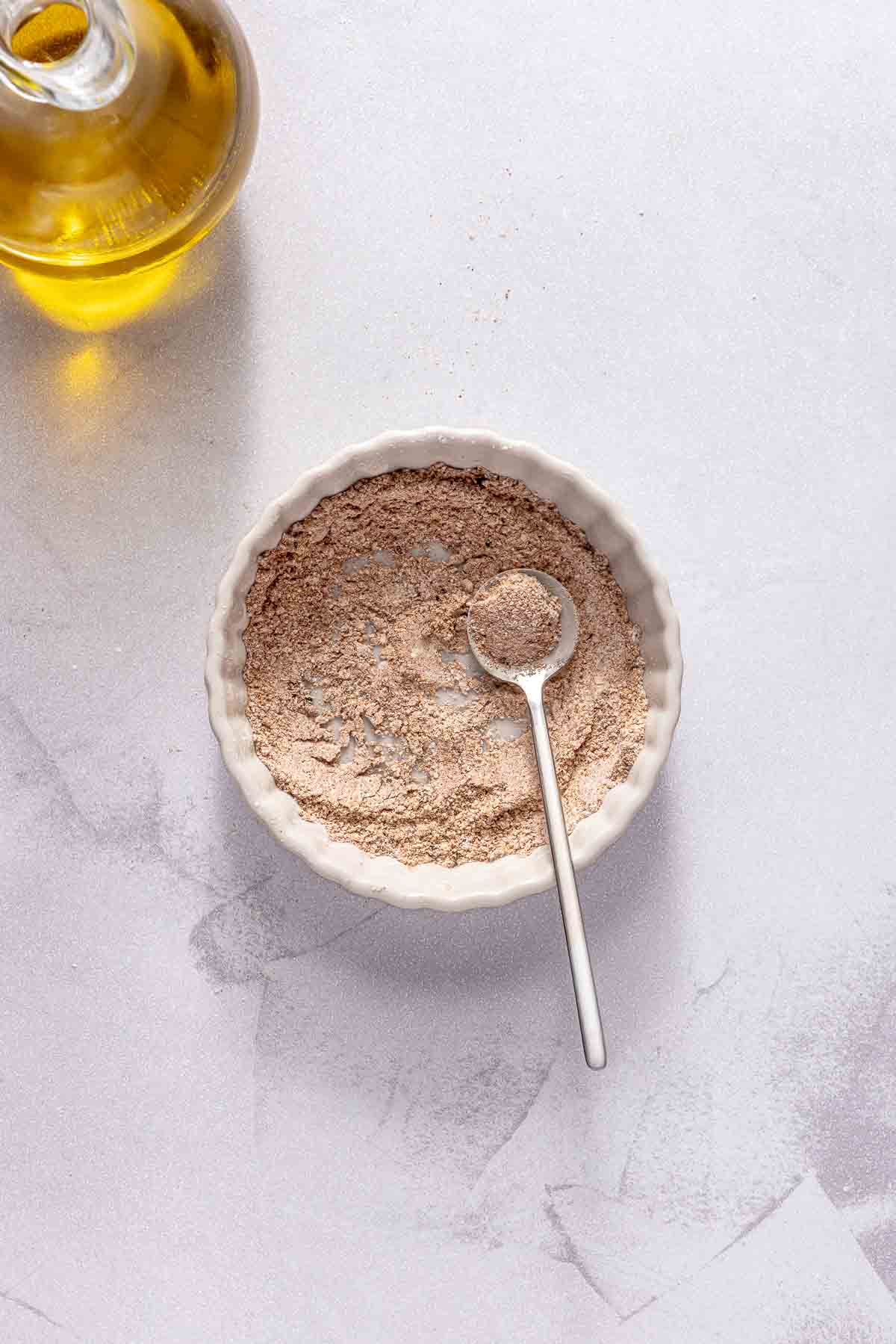 Stirring cornstarch with paprika, garlic powder, salt and pepper in a small white bowl.