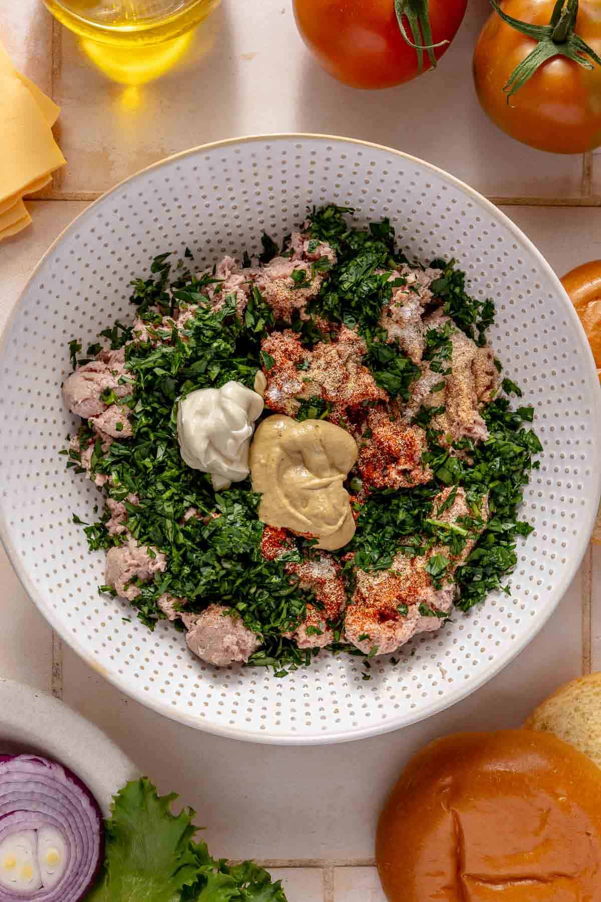 Combining ground turkey with parsley, mayo, mustard and seasonings.