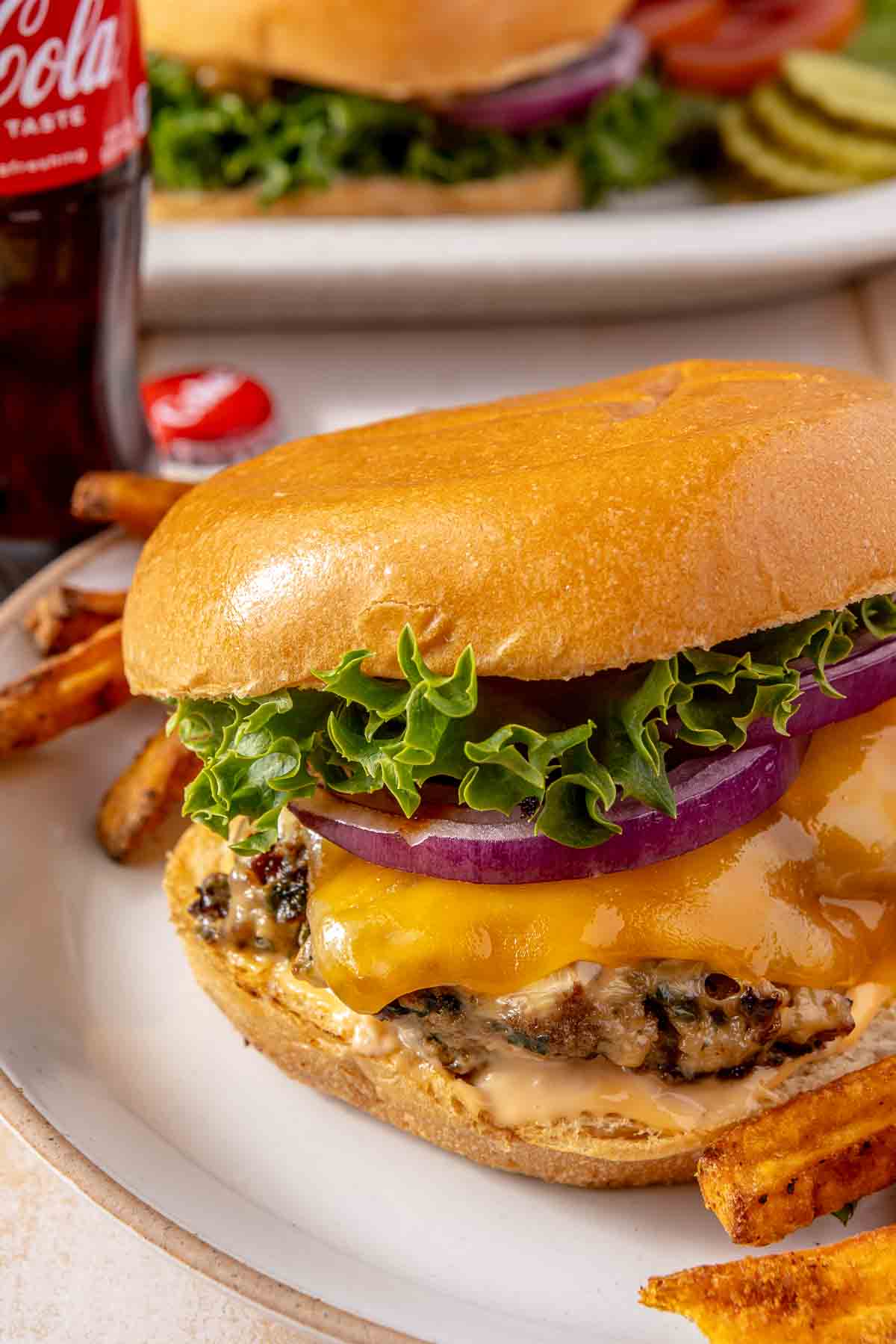 Turkey burger with cheese served on a plate with sweet potato fries.