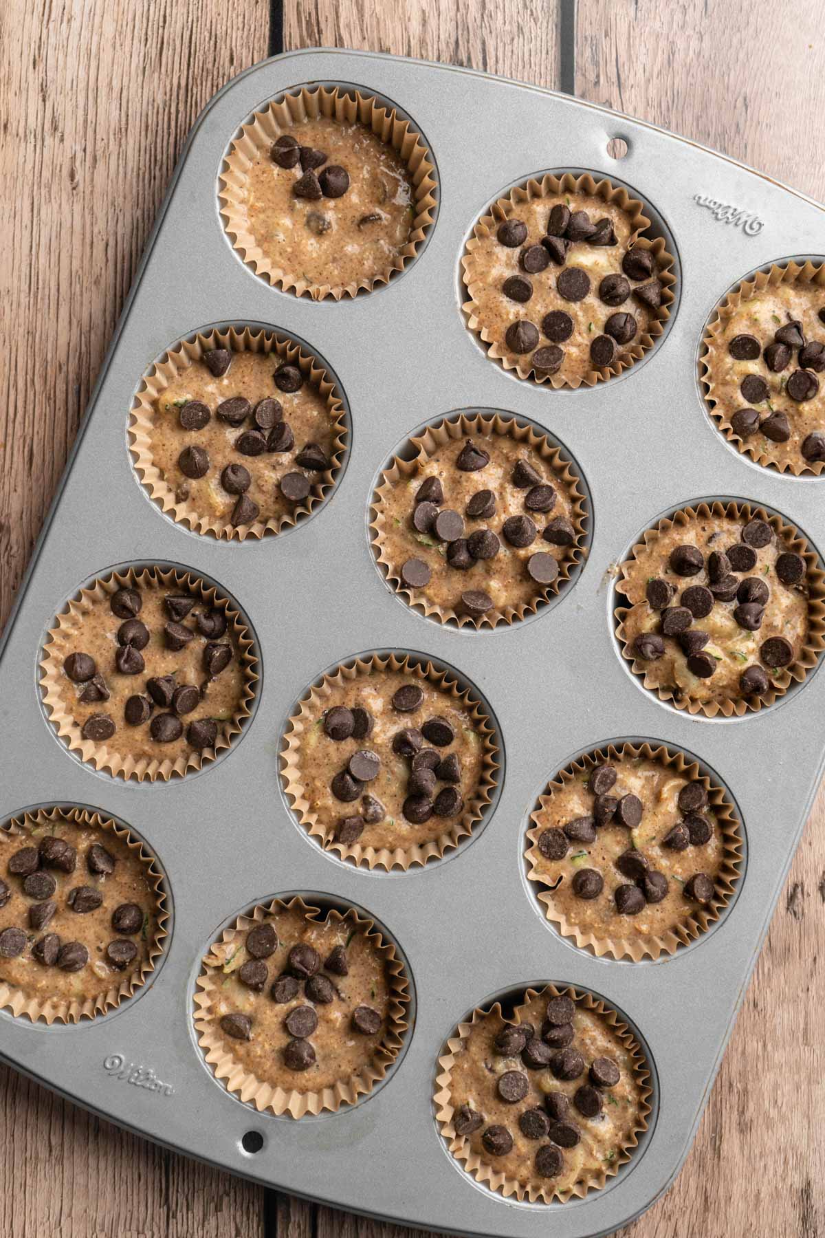 Uncooked chocolate chip muffins in a muffin pan.