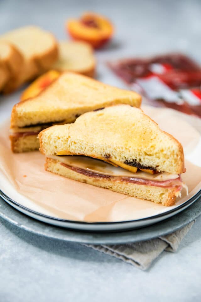 Peach Ham Grilled Cheese Sandwich cut in half and served on a white plate